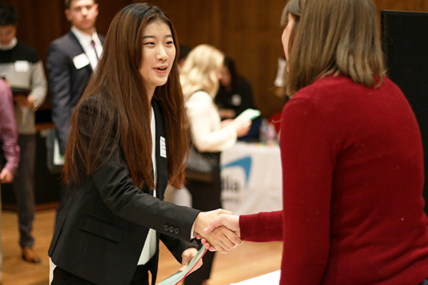 A student shaking hands with an employer at a career fair