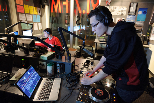 Undergraduate Jorge Estrada, wearing eyeglasses, programs music during his show "In Media Res," a live remix of electro and hip-hop music, at WSUM student radio.