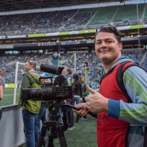 Rob Heimbruch poses on a soccer field behind his video equipment