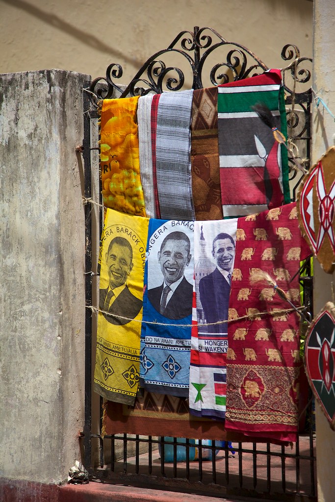 Scarves hanging on a fence in Kenya, several of which depict President Obama