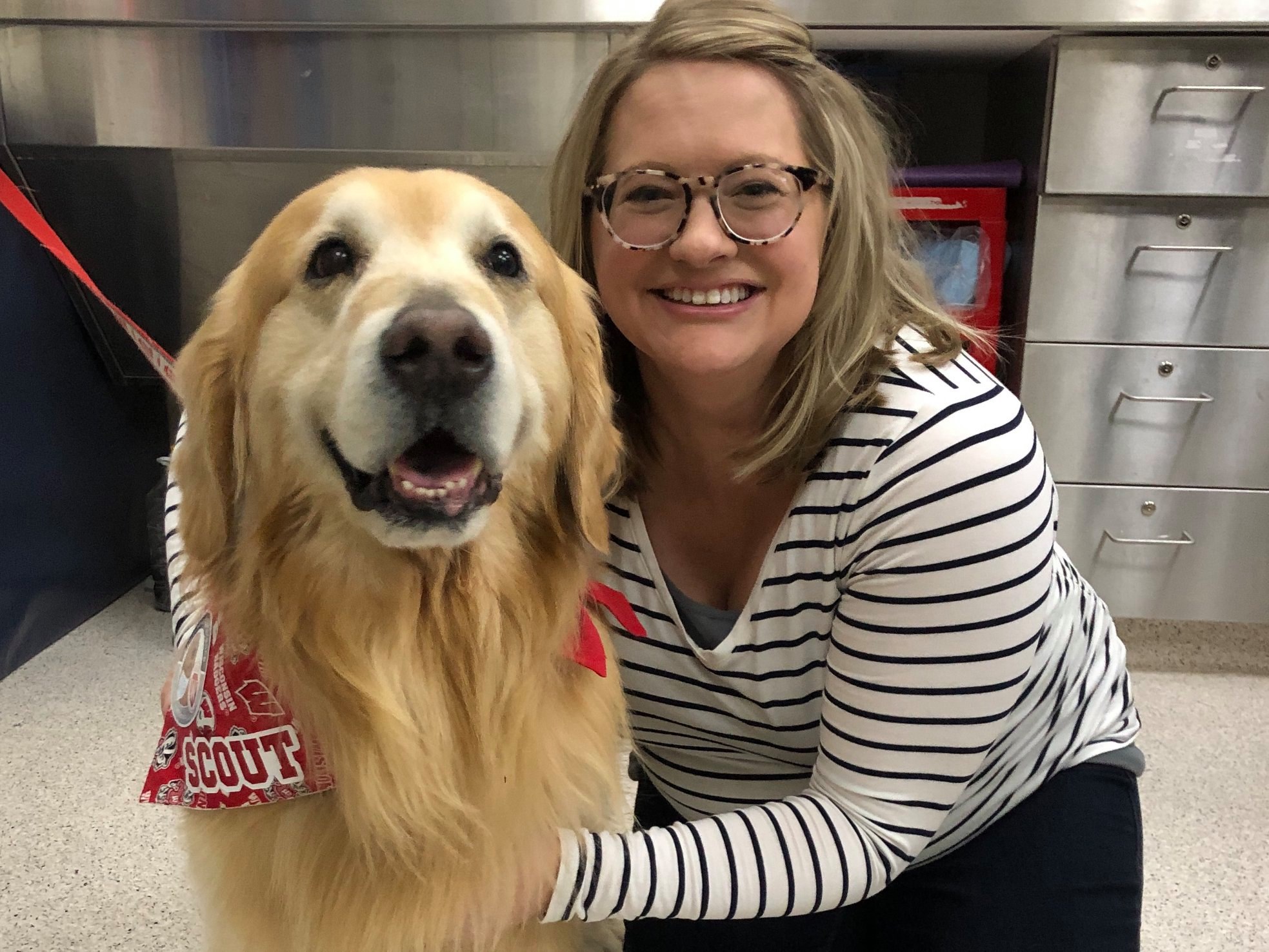 Photo of SJMC alum Ashley Voss posing with a golden retriever named Scout. 