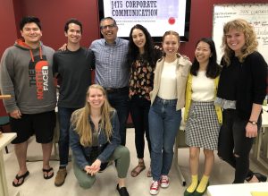 Ben Deutsch standing with a group of students in front of a monitor that reads "J475 Corporate Communication"