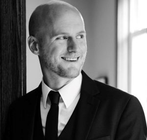 Black and white photo of a man in a suit and tie looking just right of the camera.