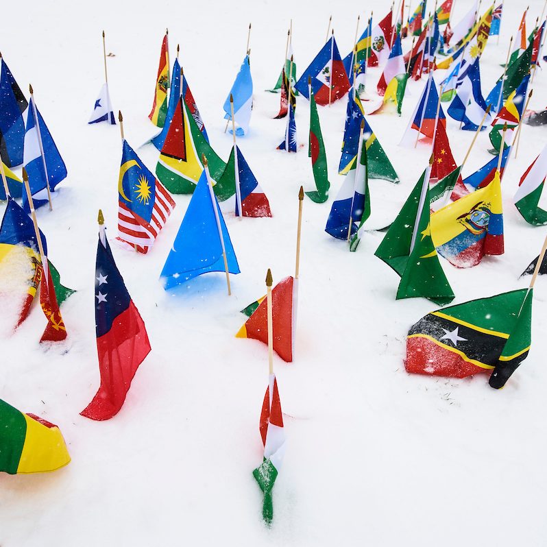 Flags from various countries stuck in the snow on Bascom Hill.