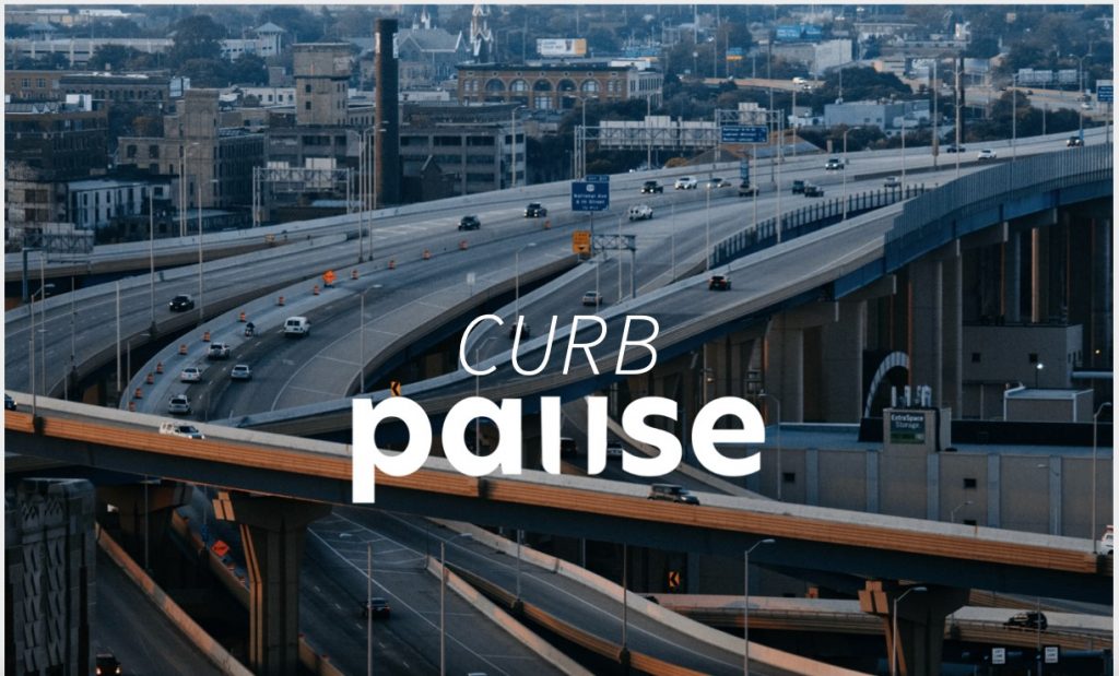 An aerial photograph of a highway interchange with the Curb Pause logo superimposed on it