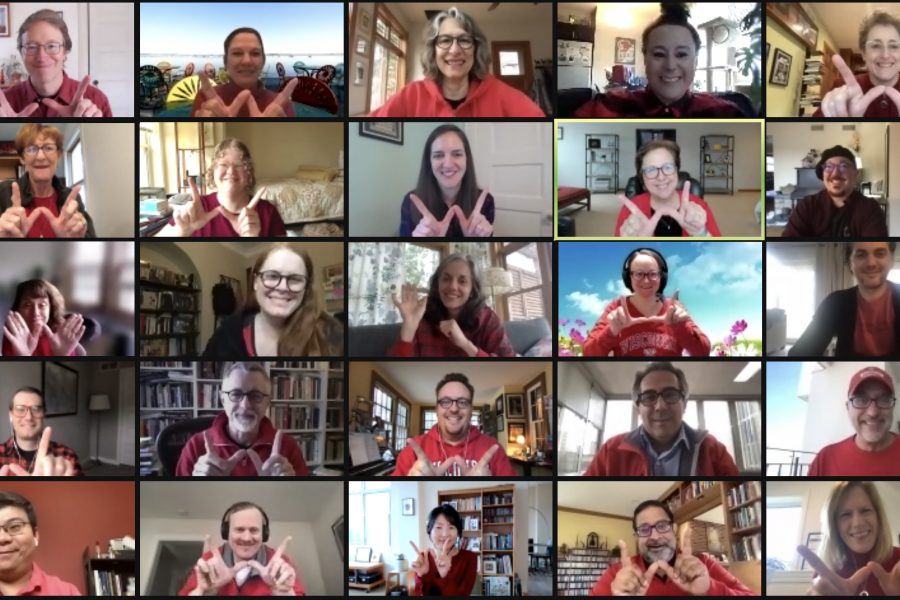 A Zoom meeting featuring the faculty and staff of the SJMC wearing red and holding their hands up in the shape of a 'W'.