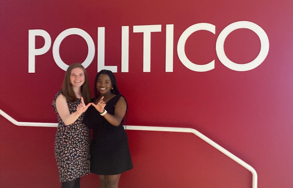 Gaby Vinick and Tamia Fowlkes in the Politico offices making a W with their hands.