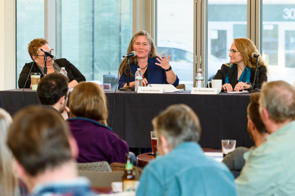 A panel of speakers seated at a table in front of a small audience.