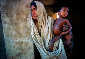 Ration card clutched in her left hand, a mother waits with her three hungry children for powdered milk donated by the U.S. and Canada during the 1974 famine in Bangladesh.