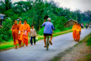 A elderly Vietnamese man tips his hat in a gesture of respect to Buddhist monks in a remote Mekong Delta village.